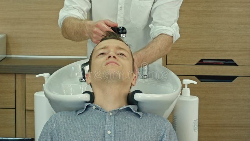Hombre hermoso que hace su pelo lavar en salón de la peluquería El hombre joven que mentía con sus ojos se cerró en salón de la b imagenes de archivo Hombre hermoso que hace su pelo lavar en salón de la peluquería El hombre joven que mentía con sus ojos se cerró en salón de la b imagenes de archivo