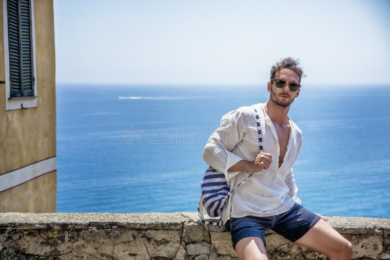 Hombre hermoso que se sienta en la ciudad de la playa fotos de archivo libres de regalías Hombre hermoso que se sienta en la ciudad de la playa fotos de archivo libres de regalías