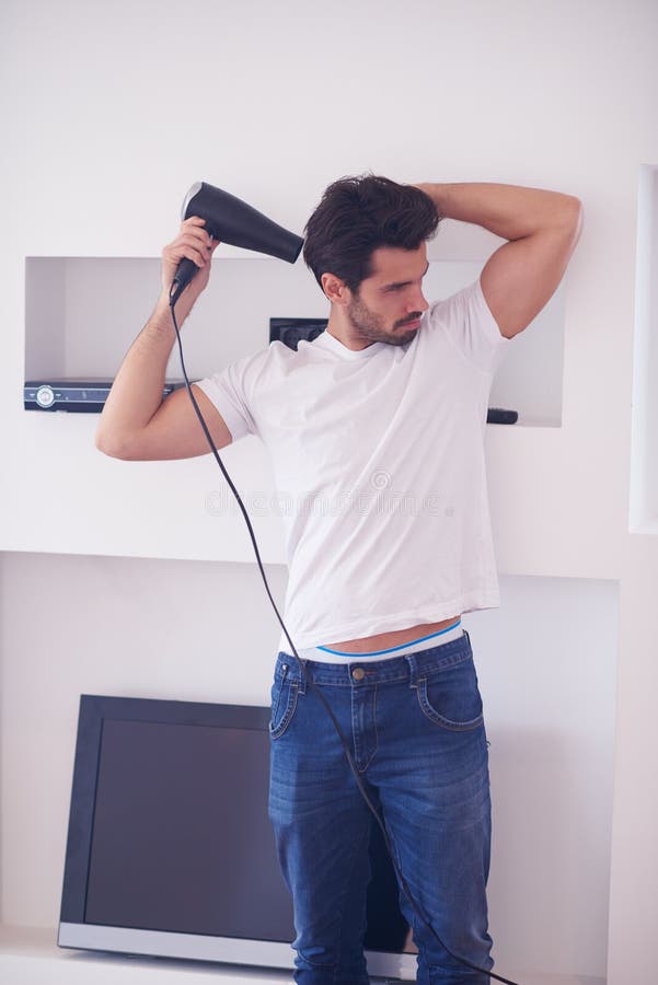 Hombre hermoso que usa el hairdryer fotos de archivo libres de regalías Hombre hermoso que usa el hairdryer fotos de archivo libres de regalías