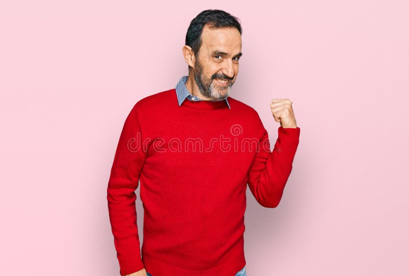 Hombre hispano de mediana edad con ropa casual sonriendo con cara feliz mirando y señalando hacia el lado con el pulgar hacia arri fotos de archivo