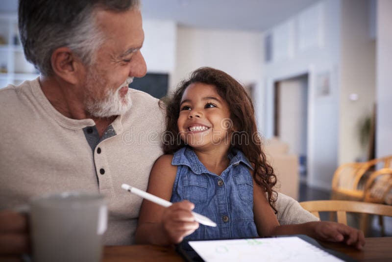 Senior Hispanic men with his granddaughter using tablet computer, looking at each other, close up. Senior Hispanic men with his granddaughter using tablet computer, looking at each other, close up