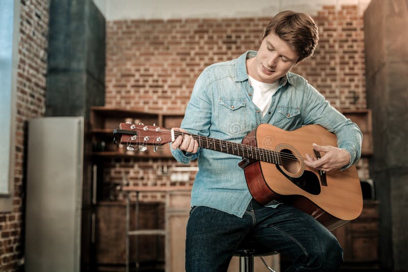 Hombre joven agradable que toca la guitarra imágenes de archivo libres de regalías Hombre joven agradable que toca la guitarra imágenes de archivo libres de regalías