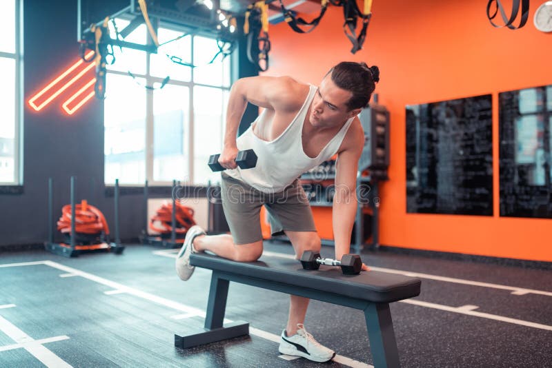Hombre joven apto que ejercita con dos pesas de gimnasia foto de archivo Hombre joven apto que ejercita con dos pesas de gimnasia foto de archivo