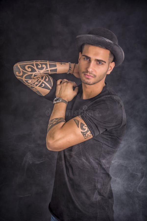 Hombre joven con el hongo y los tatuajes negros foto de archivo Hombre joven con el hongo y los tatuajes negros foto de archivo
