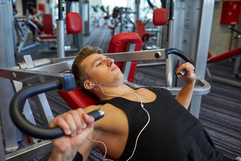 Hombre Joven Con Los Auriculares Que Ejercita En La Máquina Del Gimnasio  Imagen de archivo - Imagen de gente, deportista: 46820021