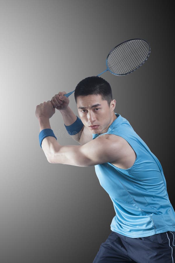 Hombre joven concentrado que juega al bádminton, estafa aumentada imagenes de archivo Hombre joven concentrado que juega al bádminton, estafa aumentada imagenes de archivo