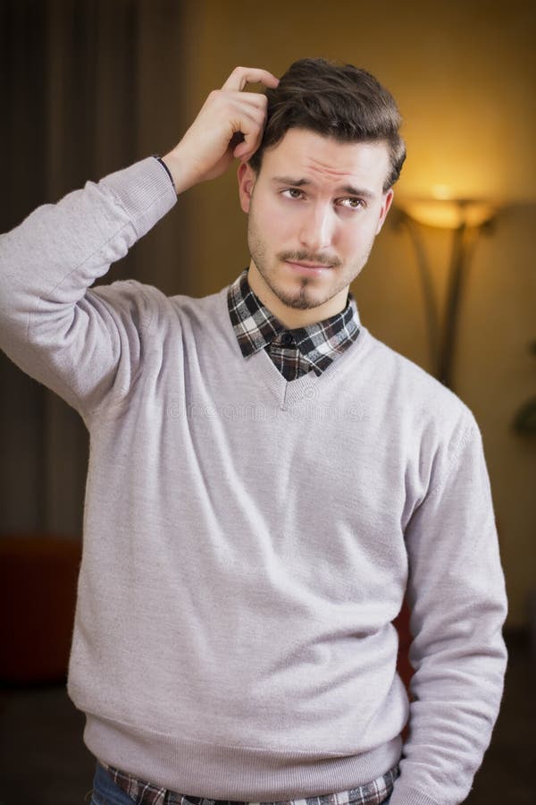 Hombre joven confuso o dudoso que rasguña su cabeza y que mira para arriba imagen de archivo Hombre joven confuso o dudoso que rasguña su cabeza y que mira para arriba imagen de archivo