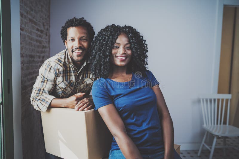 Hombre joven del africano negro y sus cajas móviles de la novia en nueva casa junto y haciendo una vida hermosa alegre fotografía de archivo libre de regalías Hombre joven del africano negro y sus cajas móviles de la novia en nueva casa junto y haciendo una vida hermosa alegre fotografía de archivo libre de regalías