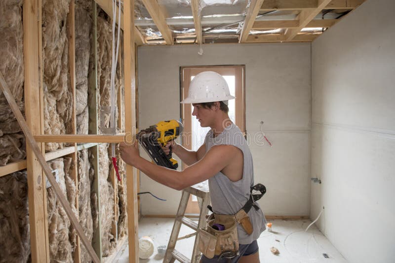 Hombre joven del aprendiz de la industria del constructor en su 20s que lleva el casco protector que aprende el trabajo con el ta imágenes de archivo libres de regalías