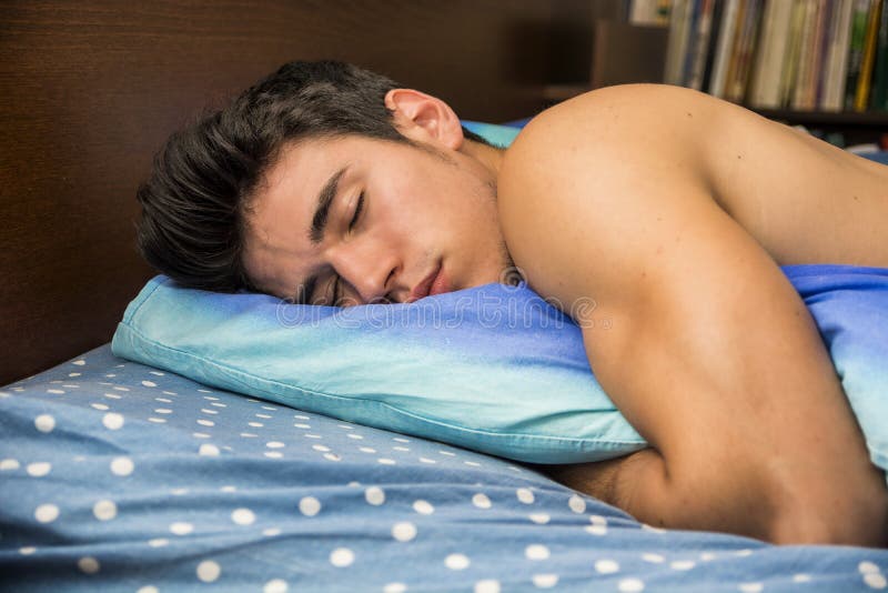 Hombre joven descamisado hermoso que duerme en cama imagen de archivo libre de regalías Hombre joven descamisado hermoso que duerme en cama imagen de archivo libre de regalías