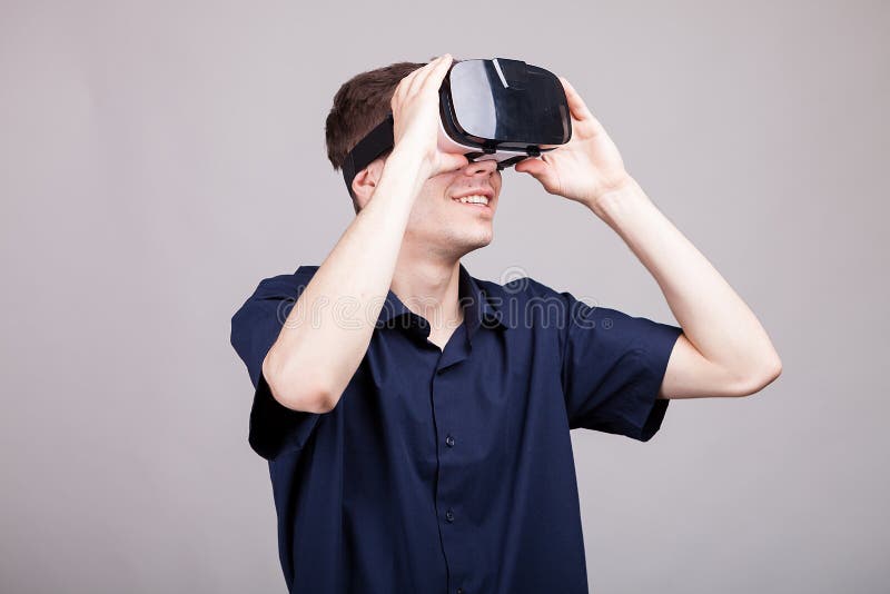 Hombre joven en la camisa azul casual que lleva auriculares de la realidad virtual de VR imágenes de archivo libres de regalías Hombre joven en la camisa azul casual que lleva auriculares de la realidad virtual de VR imágenes de archivo libres de regalías