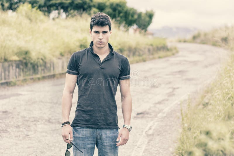 Hombre joven en vaqueros y camiseta negra que camina adelante fotografía de archivo Hombre joven en vaqueros y camiseta negra que camina adelante fotografía de archivo