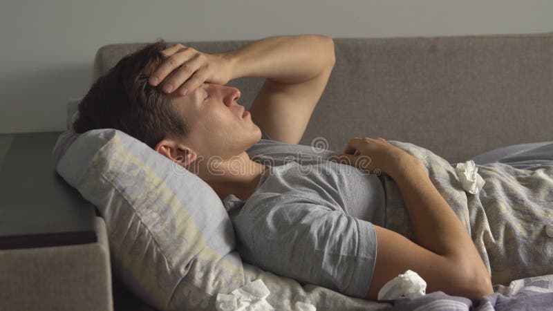 Hombre joven enfermo en cama con dolor de cabeza almacen de metraje de vídeo