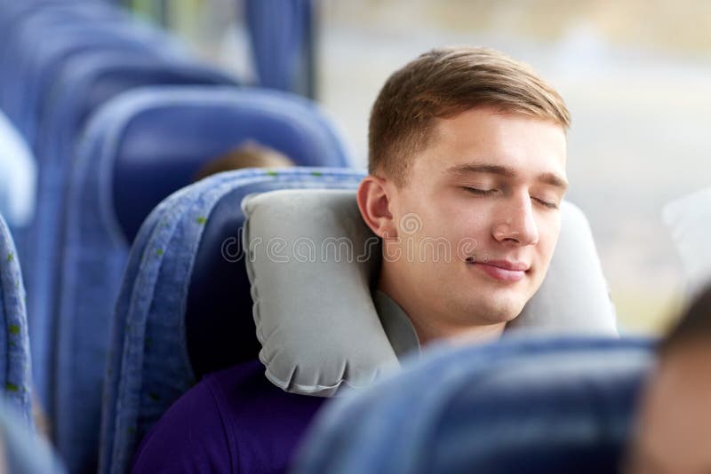 Hombre joven feliz que duerme en autobús del viaje con la almohada imagen de archivo libre de regalías Hombre joven feliz que duerme en autobús del viaje con la almohada imagen de archivo libre de regalías