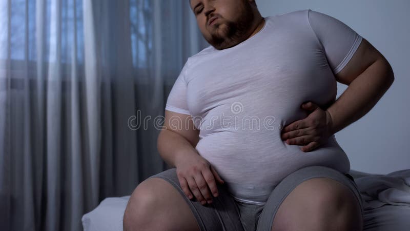 Hombre joven grande que sufre del dolor de estómago, reflujo ácido, enfermedad del higado gorda, dieta fotografía de archivo libre de regalías Hombre joven grande que sufre del dolor de estómago, reflujo ácido, enfermedad del higado gorda, dieta fotografía de archivo libre de regalías