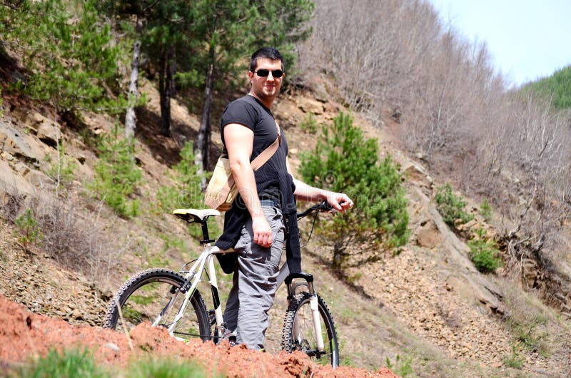 Hombre joven hermoso biking en la montaña imágenes de archivo libres de regalías Hombre joven hermoso biking en la montaña imágenes de archivo libres de regalías
