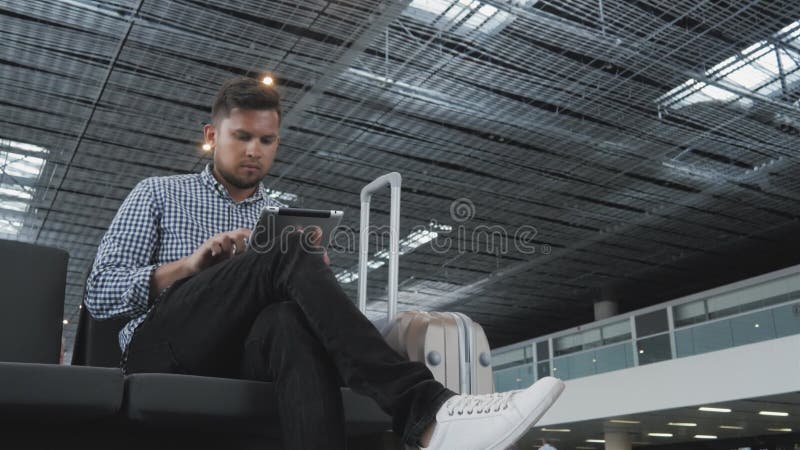Hombre joven hermoso que sostiene Tablet PC y que trabaja en el aeropuerto, tecnología, concepto que viaja fotos de archivo libres de regalías Hombre joven hermoso que sostiene Tablet PC y que trabaja en el aeropuerto, tecnología, concepto que viaja fotos de archivo libres de regalías