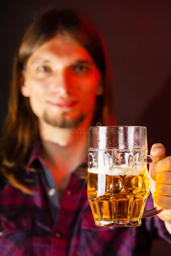 Hombre joven hermoso que sostiene una taza de cerveza foto de archivo Hombre joven hermoso que sostiene una taza de cerveza foto de archivo