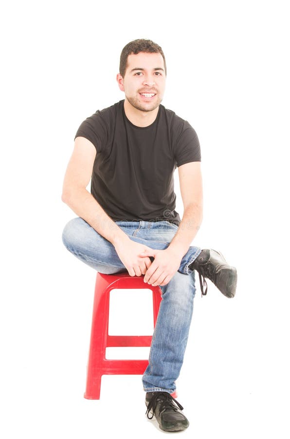 Hombre joven latino que se sienta en taburete rojo foto de archivo