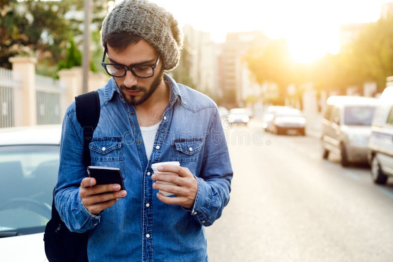 Hombre joven moderno con el teléfono móvil en la calle foto de archivo Hombre joven moderno con el teléfono móvil en la calle foto de archivo