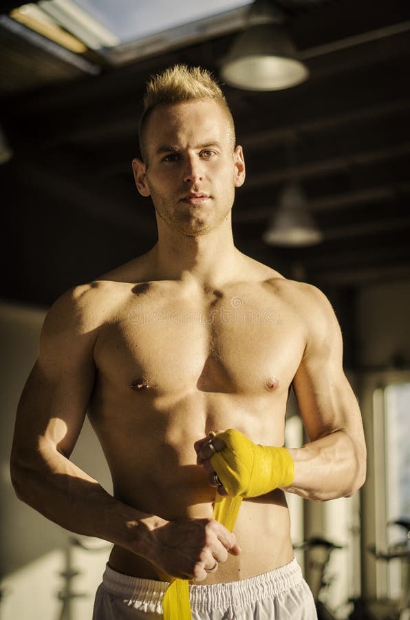 Hombre joven muscular que envuelve el vendaje alrededor de sus manos foto de archivo libre de regalías Hombre joven muscular que envuelve el vendaje alrededor de sus manos foto de archivo libre de regalías