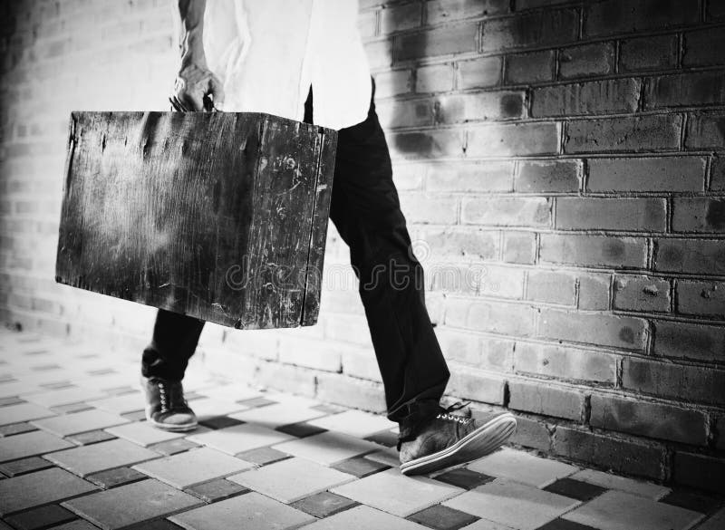Hombre joven que camina a lo largo de la calle con la maleta vieja imágenes de archivo libres de regalías Hombre joven que camina a lo largo de la calle con la maleta vieja imágenes de archivo libres de regalías
