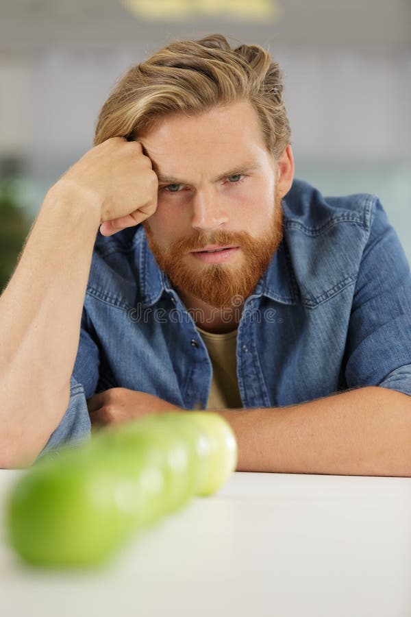 Hombre joven que mira fijamente las manzanas de la fila foto de archivo Hombre joven que mira fijamente las manzanas de la fila foto de archivo