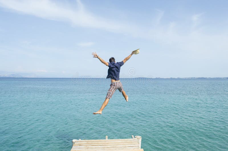 Hombre joven que salta del muelle en el mar foto de archivo libre de regalías Hombre joven que salta del muelle en el mar foto de archivo libre de regalías