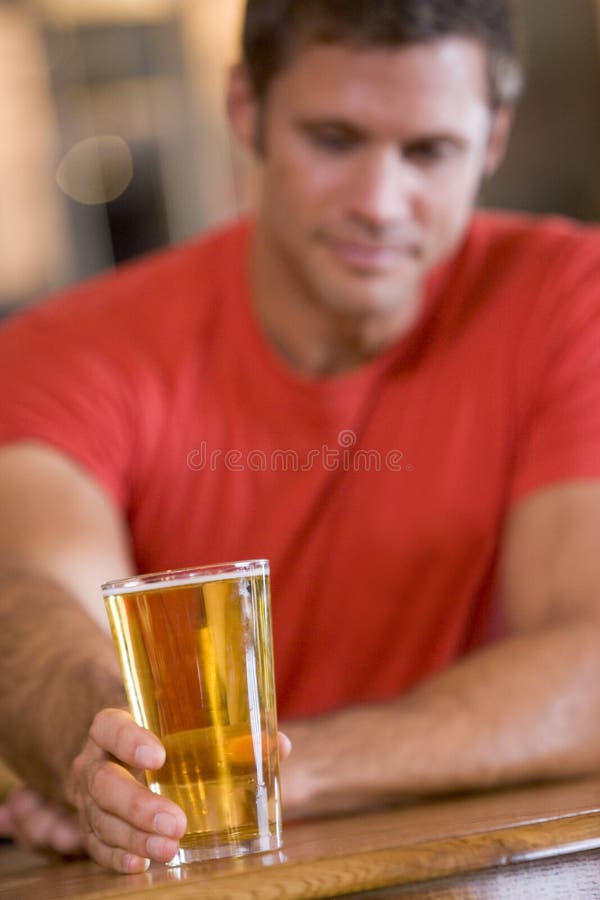 Hombre joven que se relaja en una barra con una cerveza fotos de archivo Hombre joven que se relaja en una barra con una cerveza fotos de archivo