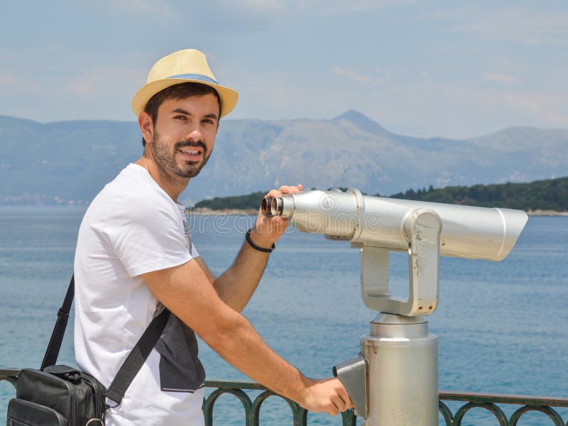 Hombre joven que sostiene los prismáticos públicos en la paja que lleva de la playa fotos de archivo Hombre joven que sostiene los prismáticos públicos en la paja que lleva de la playa fotos de archivo