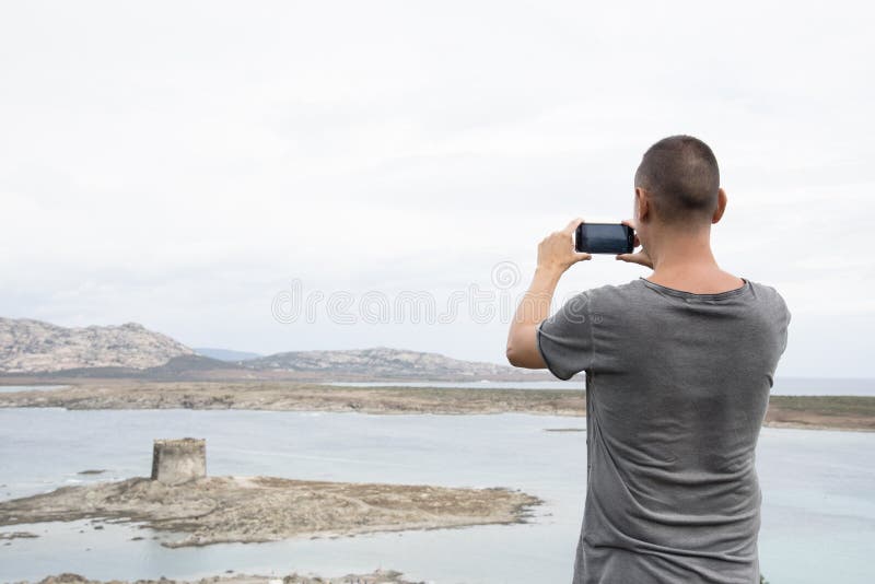 Hombre joven que toma una imagen en Cerdeña, Italia imágenes de archivo libres de regalías Hombre joven que toma una imagen en Cerdeña, Italia imágenes de archivo libres de regalías