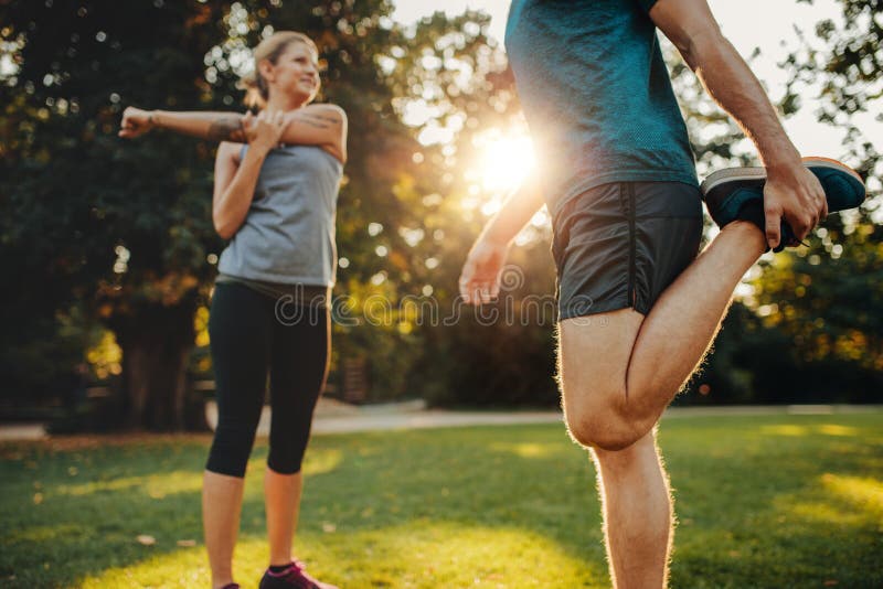 Hombre joven y mujer que estiran en el parque imagenes de archivo Hombre joven y mujer que estiran en el parque imagenes de archivo