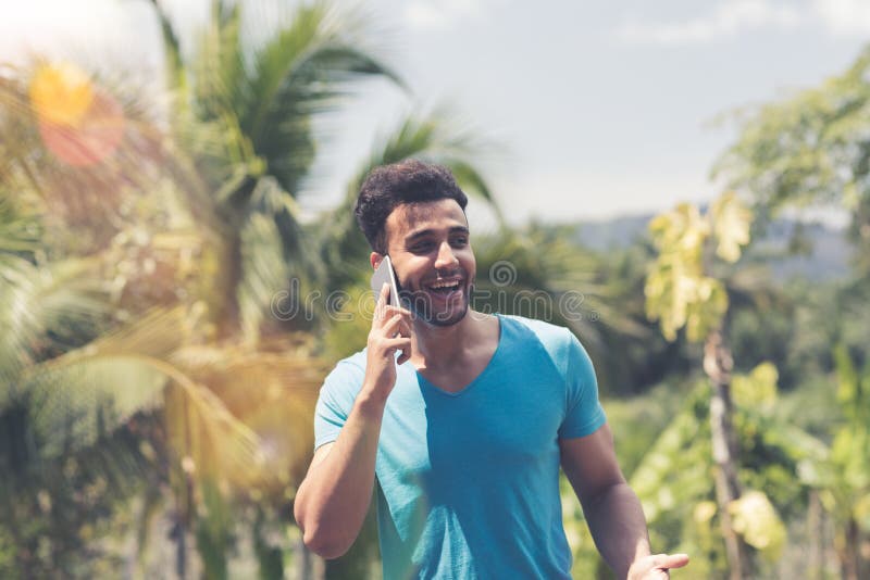 Hombre latino que hace llamada de teléfono sobre individuo sonriente feliz tropical de la raza de la mezcla de Forest And Blue Sk imagen de archivo Hombre latino que hace llamada de teléfono sobre individuo sonriente feliz tropical de la raza de la mezcla de Forest And Blue Sk imagen de archivo