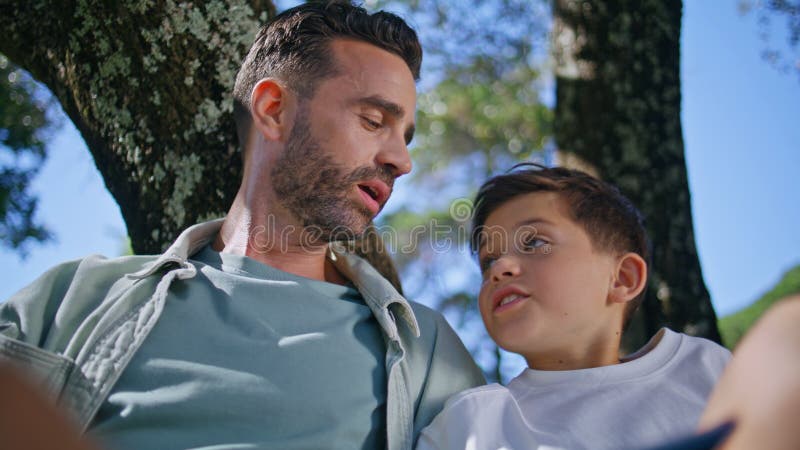 Hombre leyendo cuento de hadas sentado en un armario forestal. Padres y niños descansando imágenes de archivo libres de regalías