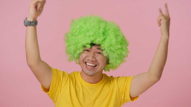 Hombre loco joven con la peluca afro coloreada que expresa felicidad