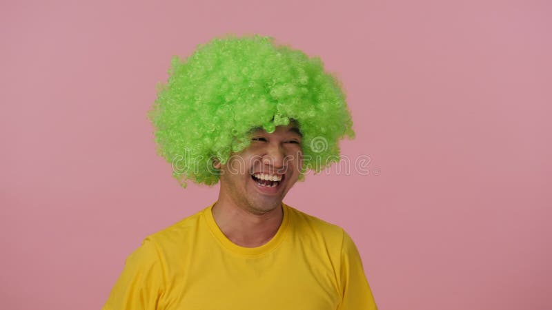 Hombre loco joven con la peluca afro coloreada que expresa felicidad