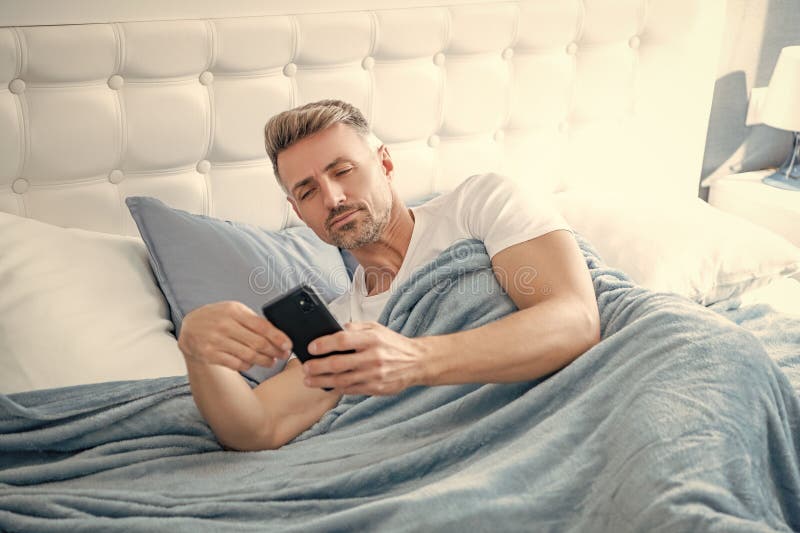 Hombre maduro en la cama charlando por teléfono fotos de archivo libres de regalías