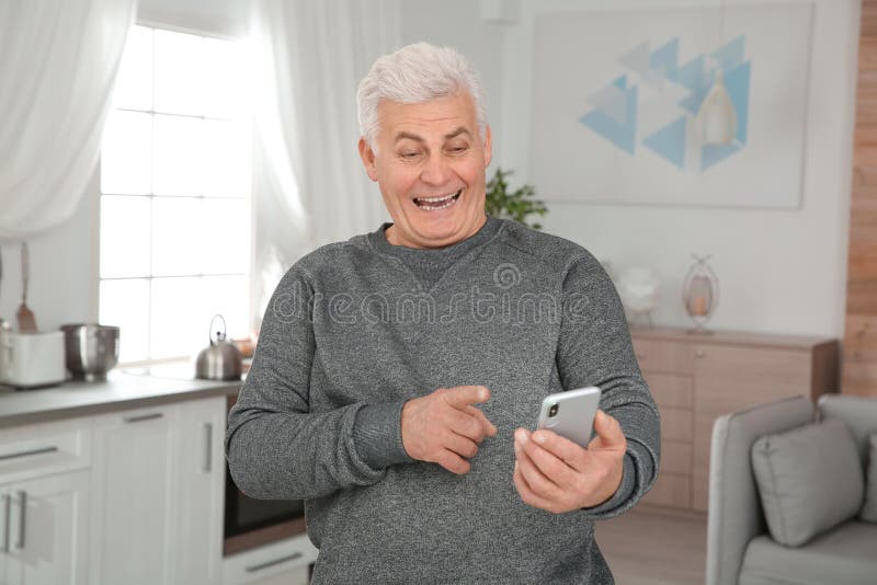 Hombre maduro que ríe mientras que usando smartphone imagenes de archivo Hombre maduro que ríe mientras que usando smartphone imagenes de archivo