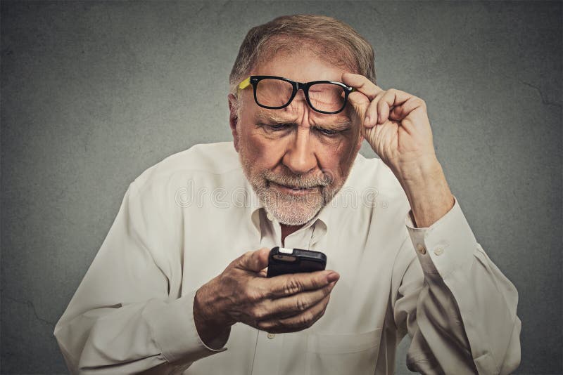 Hombre mayor con los vidrios que tienen problema que ve el teléfono celular