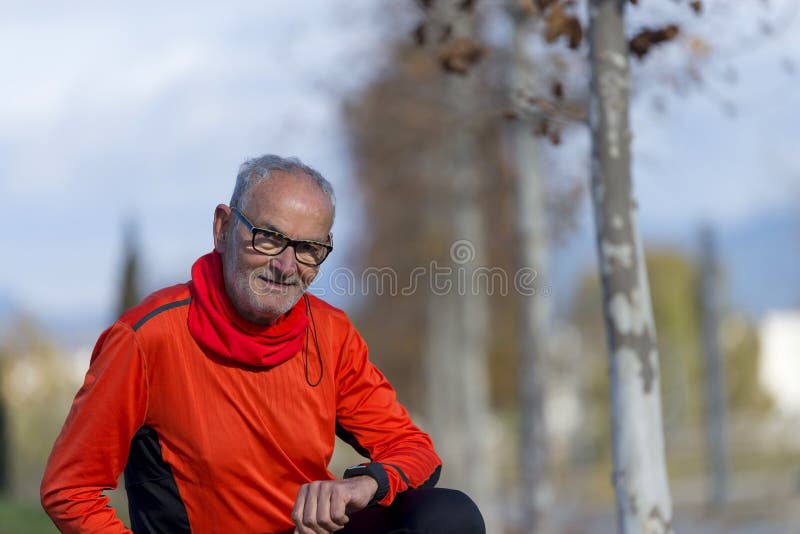 Hombre mayor del corredor que descansa en el parque mientras que supervisa su exerc imagen de archivo Hombre mayor del corredor que descansa en el parque mientras que supervisa su exerc imagen de archivo