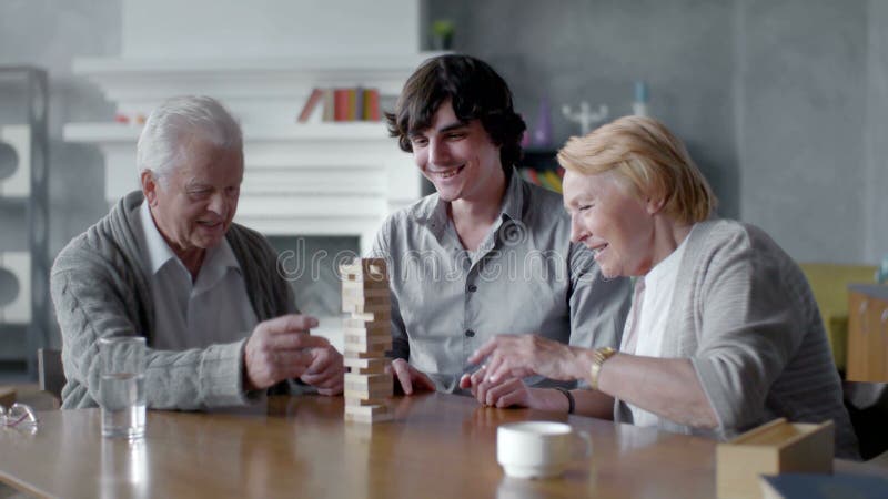 Hombre mayor feliz y mujer que juegan al juego de mesa con su nieto