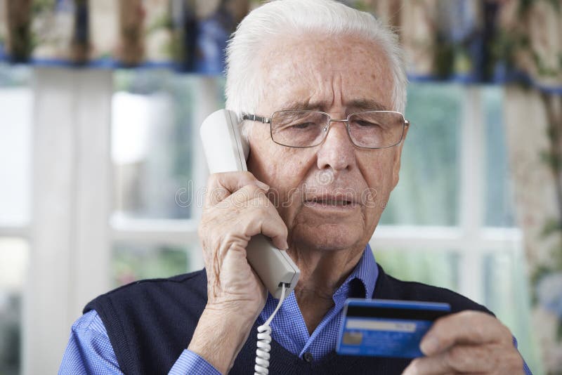 Hombre mayor que da los detalles de la tarjeta de crédito en el teléfono