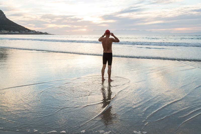 Hombre mayor que se prepara para nadar en el mar en el amanecer imagen de archivo libre de regalías Hombre mayor que se prepara para nadar en el mar en el amanecer imagen de archivo libre de regalías