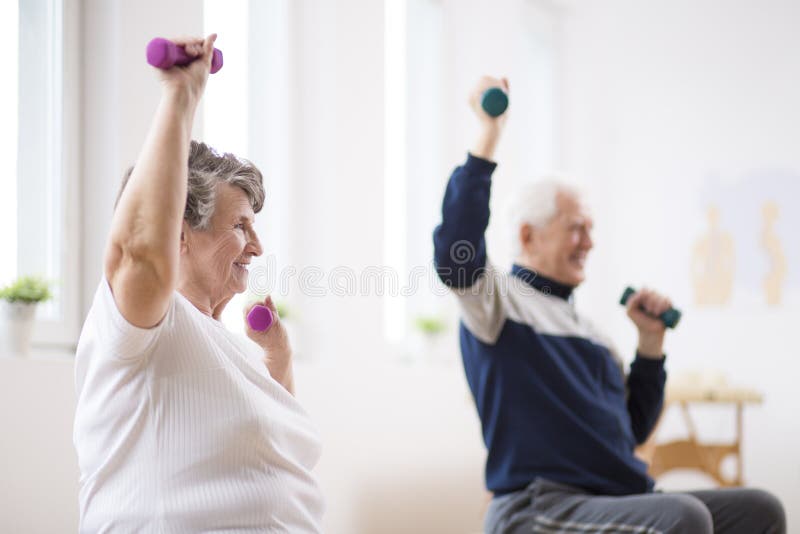 Hombre mayor y mujer que ejercitan con pesas de gimnasia durante la sesión de la fisioterapia en el hospital
