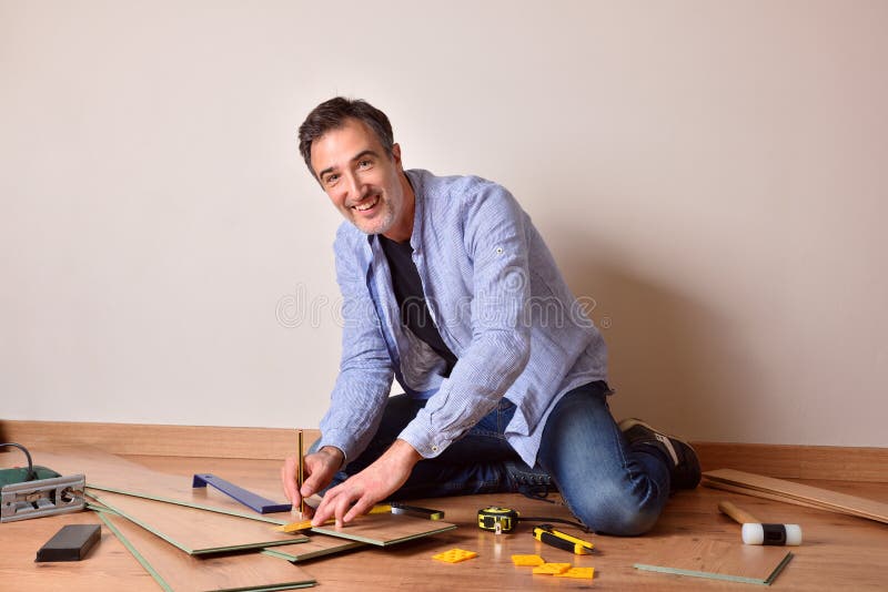 Hombre midiendo e instalando parquet laminado en su propia casa foto de archivo libre de regalías