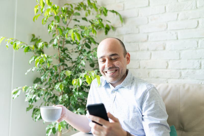 Hombre mirando un smartphone y relajándose en casa imagenes de archivo