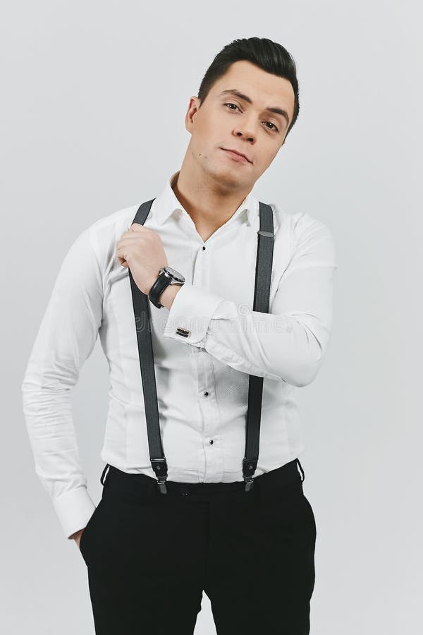 Hombre Moreno Joven De Moda Elegante En La Camisa Blanca, Pantalones Y Ligas En El Blanco Imagen de archivo - Imagen de persona, individuo: