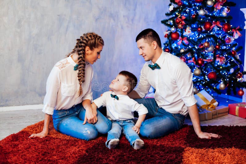 Hombre mujer e hijo pequeño sentados en el árbol de Navidad año nuevo regalos de invierno festivo fotos de archivo libres de regalías