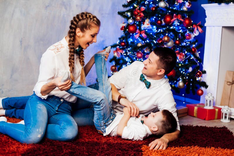 Hombre mujer e hijo pequeño sentados en el árbol de Navidad año nuevo regalos de invierno festivo foto de archivo