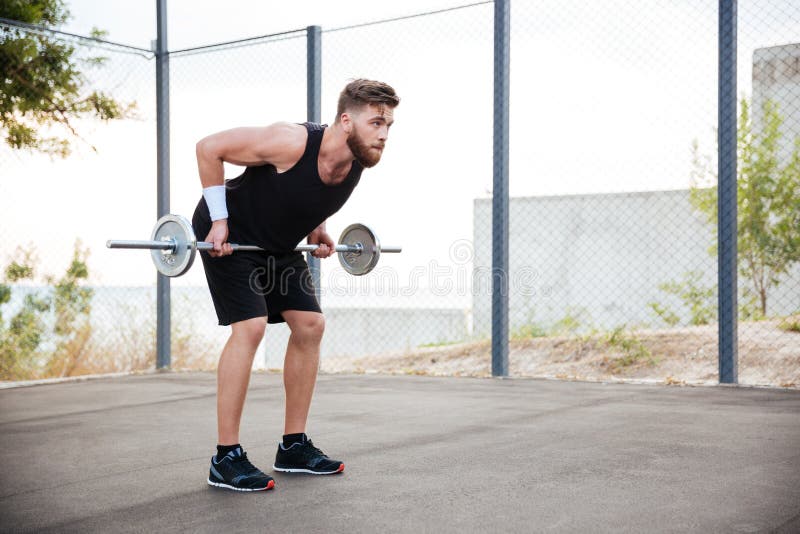 Hombre muscular de la aptitud que hace ejercicio pesado usando barbell foto de archivo Hombre muscular de la aptitud que hace ejercicio pesado usando barbell foto de archivo